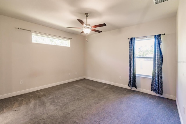 spare room with dark colored carpet, ceiling fan, and baseboards