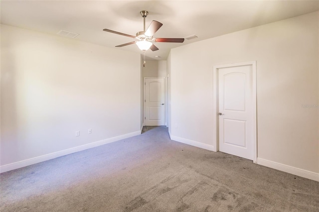 empty room featuring carpet floors, baseboards, visible vents, and a ceiling fan