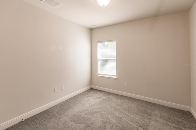 spare room featuring baseboards, visible vents, and light colored carpet