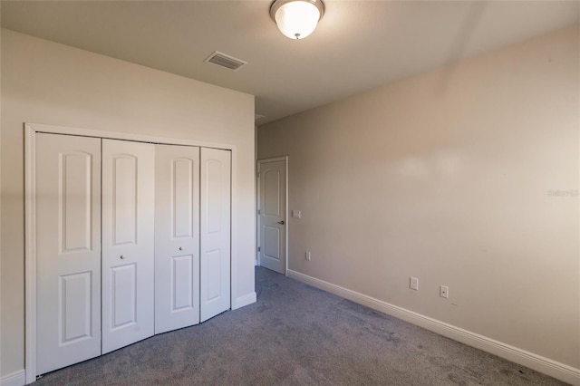 unfurnished bedroom with dark colored carpet, a closet, visible vents, and baseboards