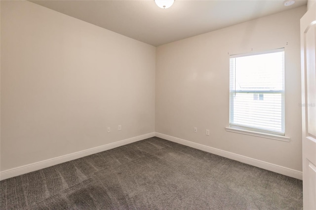 empty room featuring baseboards and dark carpet