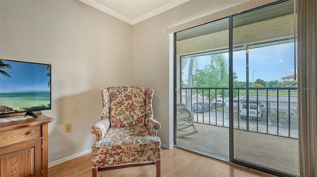 living area with light wood-style floors, baseboards, and crown molding