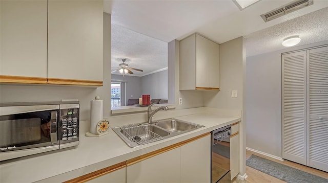 kitchen featuring black dishwasher, light countertops, stainless steel microwave, visible vents, and a sink