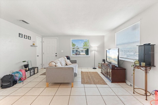 tiled living room with a textured ceiling, plenty of natural light, and visible vents