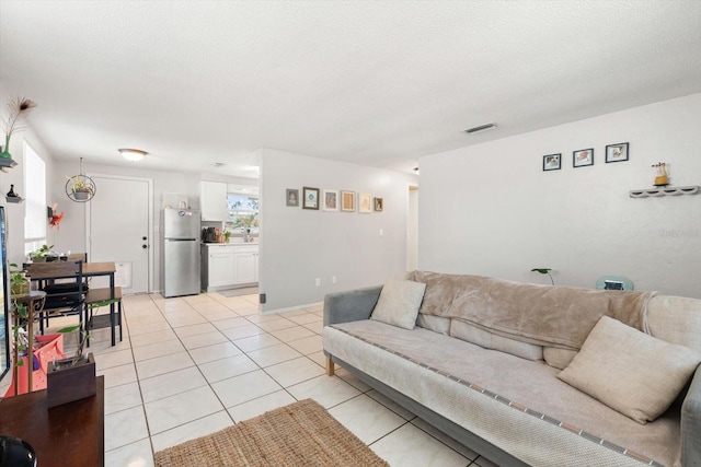 living room featuring light tile patterned floors, a textured ceiling, and visible vents