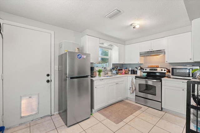 kitchen with light countertops, visible vents, appliances with stainless steel finishes, a sink, and under cabinet range hood