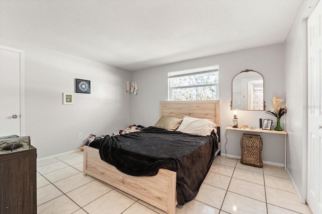 bedroom featuring light tile patterned floors, baseboards, and a textured ceiling