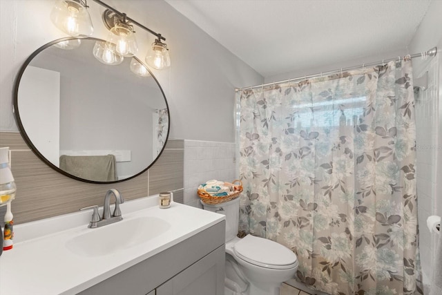 bathroom with toilet, a shower with shower curtain, vanity, tile walls, and wainscoting