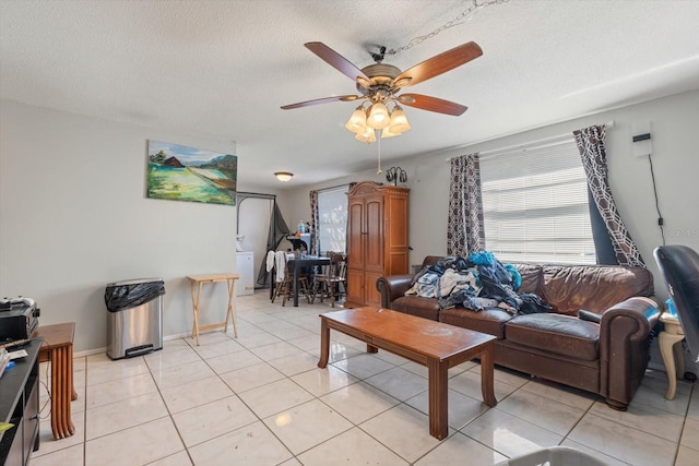 living area with a ceiling fan, a textured ceiling, baseboards, and light tile patterned floors