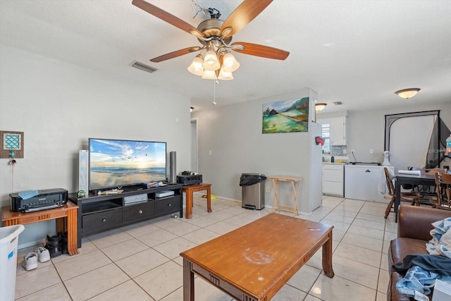 living area with ceiling fan, a textured ceiling, light tile patterned flooring, visible vents, and baseboards