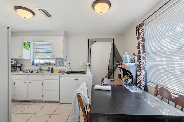 kitchen featuring light tile patterned floors, a sink, visible vents, white cabinetry, and light countertops