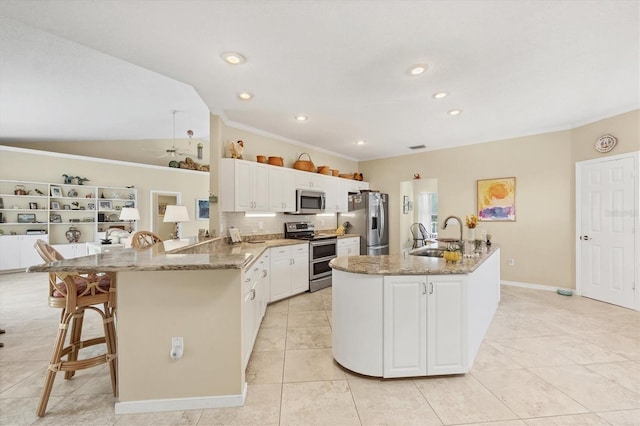 kitchen featuring appliances with stainless steel finishes, a peninsula, vaulted ceiling, white cabinetry, and a sink