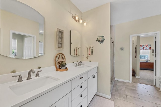 full bath featuring double vanity, tile patterned flooring, a sink, and baseboards