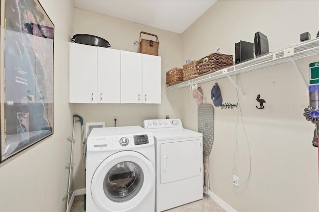 washroom featuring cabinet space, baseboards, and washer and clothes dryer