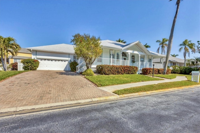 view of front of house with a garage, a porch, a front lawn, and decorative driveway