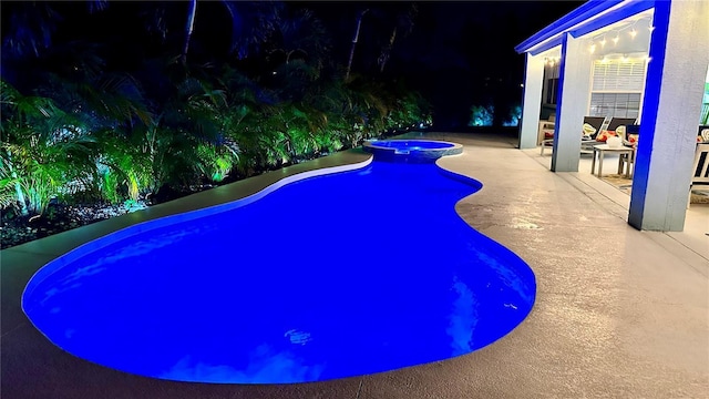 pool at twilight with a pool with connected hot tub and a patio