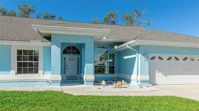 view of front facade featuring a garage, concrete driveway, a shingled roof, and stucco siding