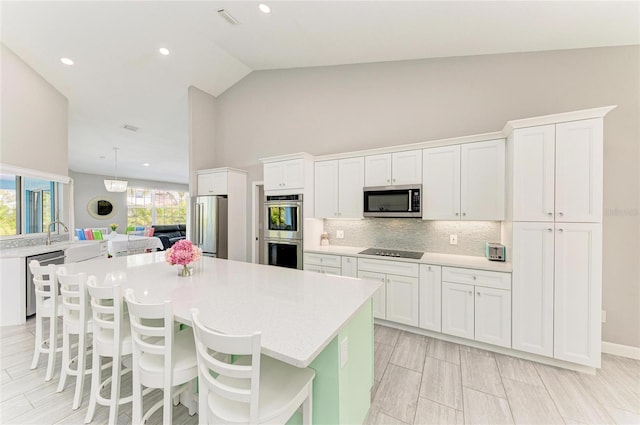 kitchen with stainless steel appliances, light countertops, backsplash, and white cabinetry