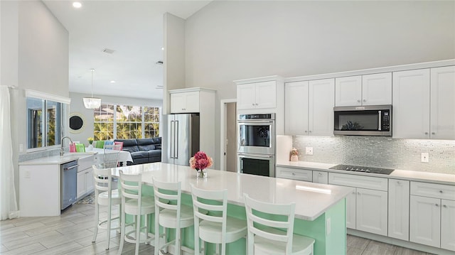 kitchen featuring appliances with stainless steel finishes, white cabinets, light countertops, and decorative backsplash