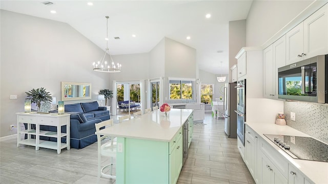 kitchen with stainless steel appliances, white cabinetry, light countertops, backsplash, and a kitchen bar