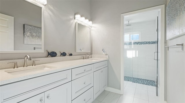 bathroom featuring double vanity, a stall shower, a sink, and baseboards