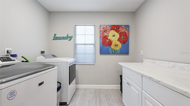 washroom featuring washer and clothes dryer, cabinet space, and baseboards