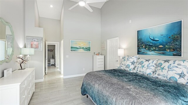 bedroom with ceiling fan, light wood finished floors, a towering ceiling, and baseboards