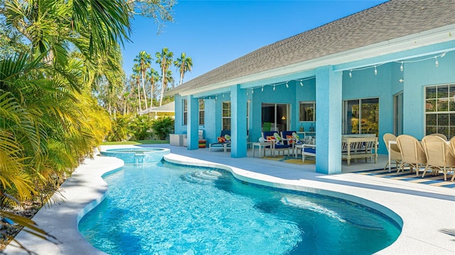 outdoor pool featuring a hot tub and a patio