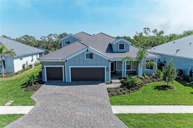 view of front facade featuring a garage, central AC unit, decorative driveway, board and batten siding, and a front yard