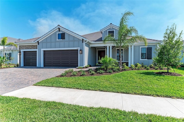 view of front of home featuring board and batten siding, a front yard, decorative driveway, and a garage