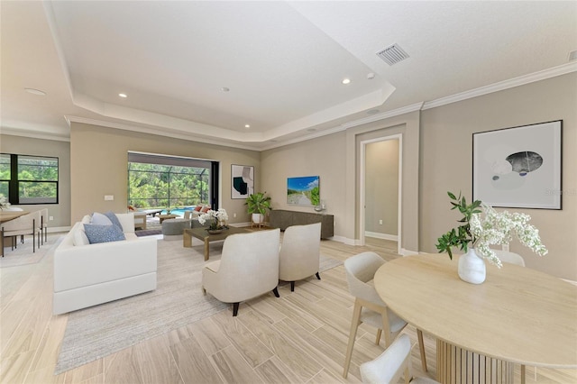 living area with a tray ceiling, visible vents, and baseboards