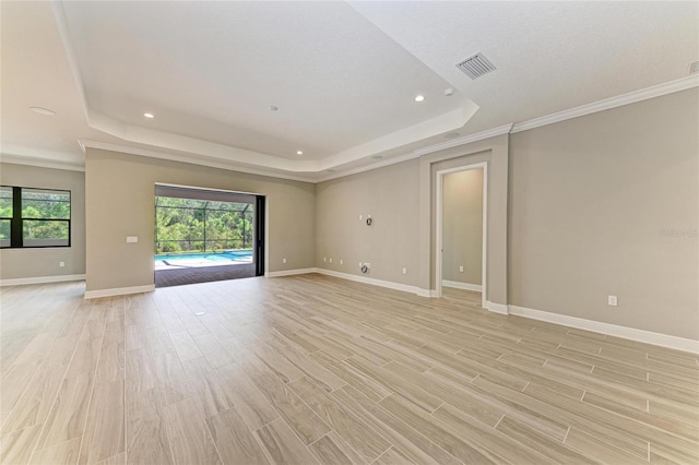 unfurnished room with light wood finished floors, baseboards, visible vents, and a raised ceiling