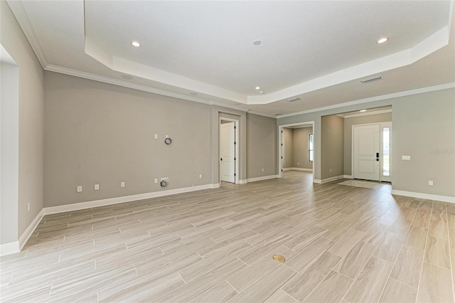 unfurnished living room with light wood-type flooring, a raised ceiling, crown molding, and baseboards