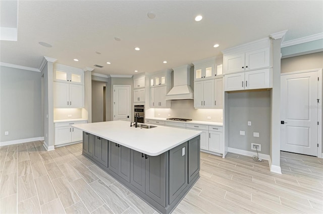 kitchen with a large island, a sink, white cabinetry, and custom range hood