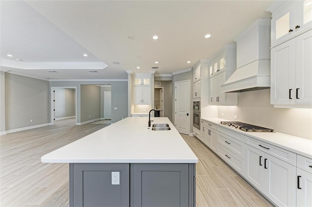 kitchen featuring appliances with stainless steel finishes, light countertops, wood finish floors, premium range hood, and a sink