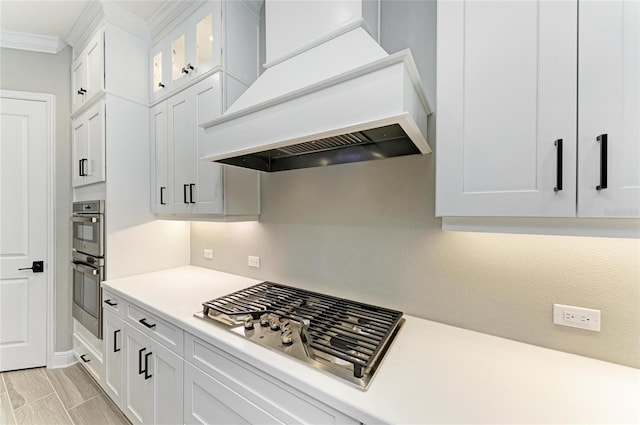 kitchen with custom range hood, appliances with stainless steel finishes, light countertops, and crown molding