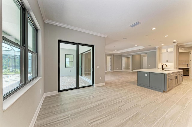 kitchen featuring a kitchen island with sink, a sink, visible vents, open floor plan, and light countertops