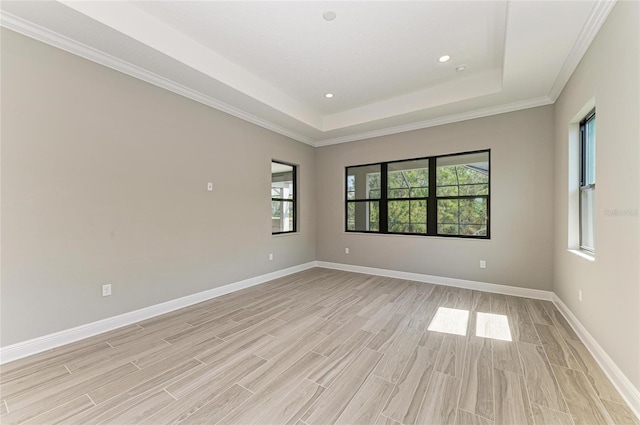 spare room with recessed lighting, a raised ceiling, light wood-style flooring, and baseboards