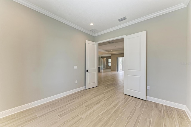 spare room featuring crown molding, wood finish floors, visible vents, and baseboards