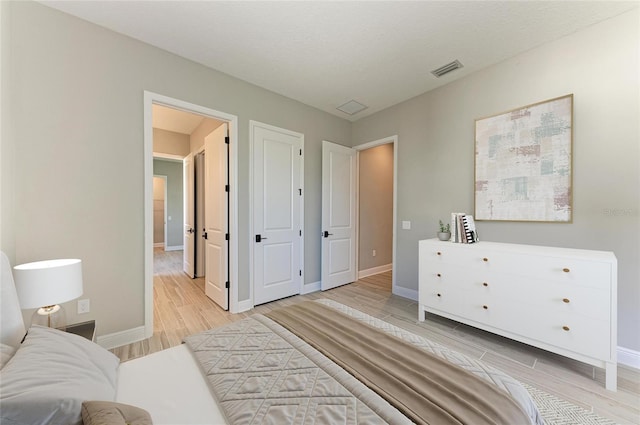 bedroom featuring light wood-type flooring, visible vents, and baseboards