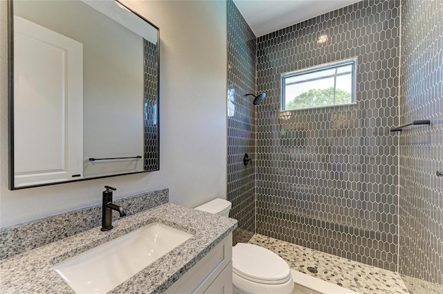 bathroom with tiled shower, vanity, and toilet