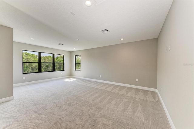 empty room with light colored carpet, visible vents, baseboards, and recessed lighting