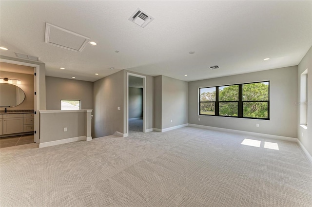 unfurnished room featuring light carpet, attic access, visible vents, baseboards, and recessed lighting