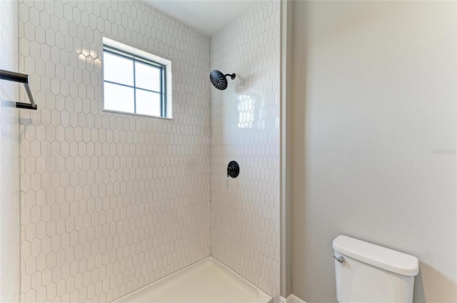 full bathroom with tiled shower and toilet