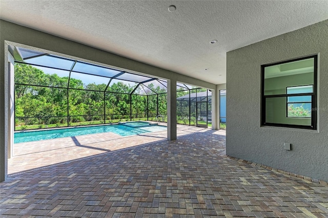 view of pool featuring a lanai, a pool with connected hot tub, and a patio