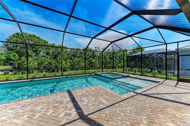 view of pool featuring glass enclosure, a pool with connected hot tub, and a patio area