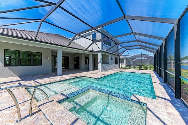 view of pool featuring a pool with connected hot tub, a patio area, and a lanai