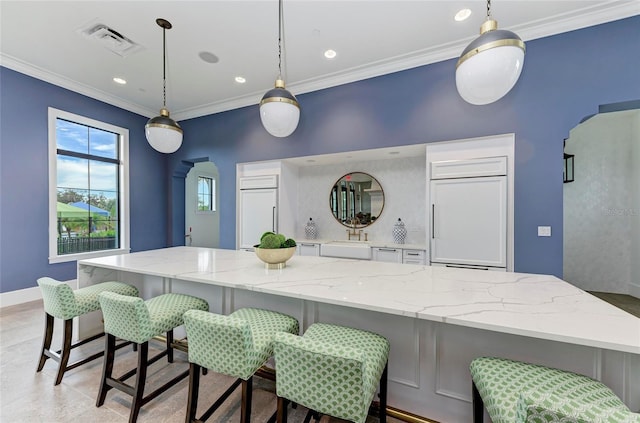 kitchen with arched walkways, paneled fridge, ornamental molding, and visible vents