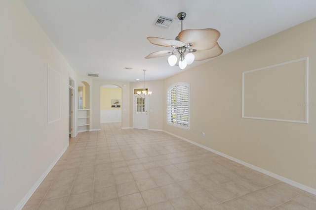 unfurnished room with baseboards, visible vents, arched walkways, and ceiling fan with notable chandelier