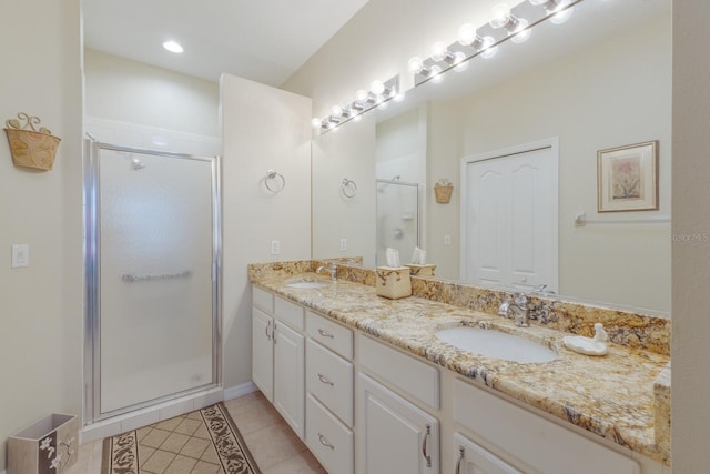 bathroom featuring double vanity, a shower stall, a sink, and tile patterned floors